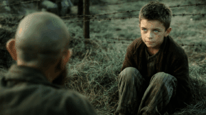 Quién es El niño del pijama de rayas caminando junto a la alambrada del campo